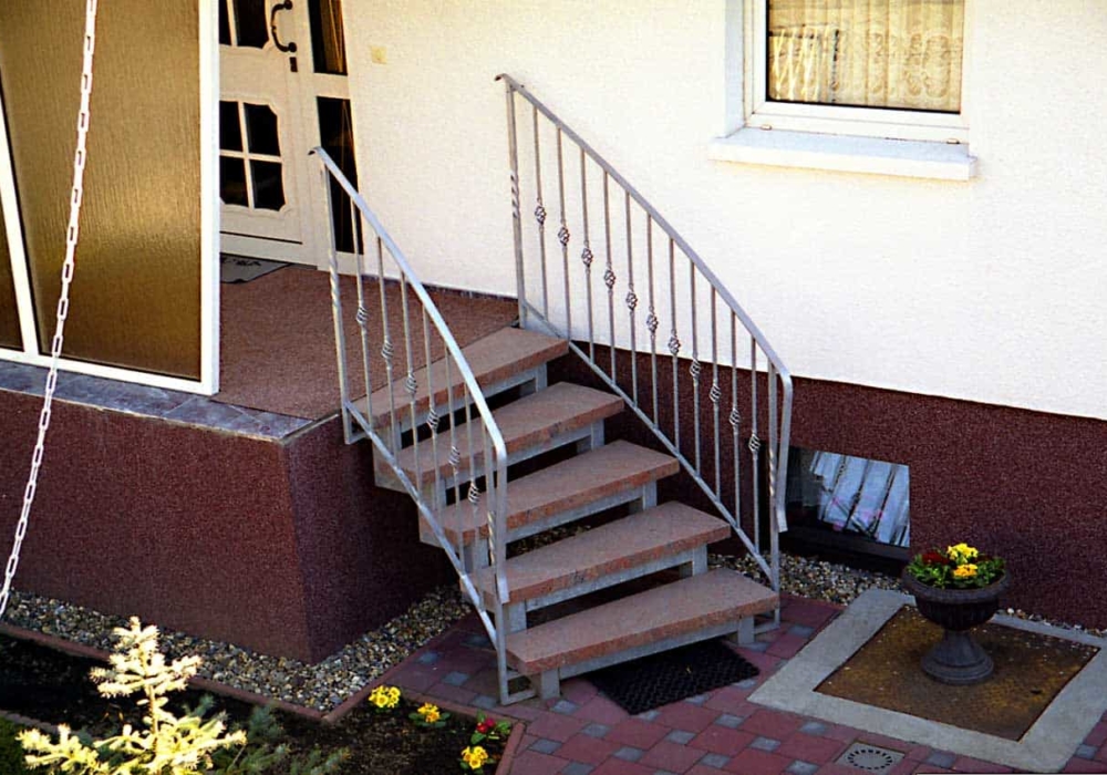 Außentreppe Stahlwangentreppe gebogen mit Podest verzinket mit beidseitigem gebogenen Geländer & Zierstäben & Flachstahl Handlauf & 60 mm Granit Stufen Rosso Balmoral geflammt