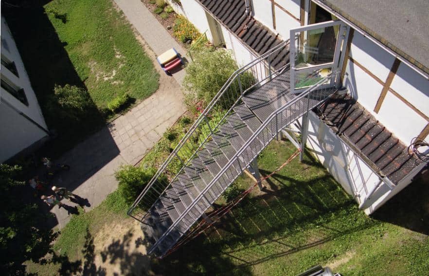 Stahl Außentreppe Geradläufig verzinkt auf Stützen stehend als Außen Zugang zum 1 OG mit Podest & beidseitigem Treppengeländer als Wangen Konstruktion & Rundrohr Geländerstäben & Handlauf & Gitterroststufen