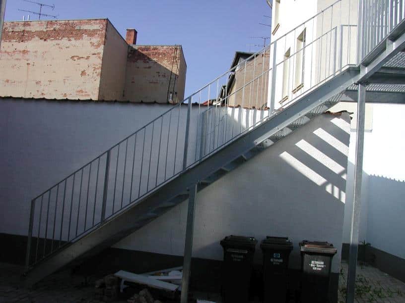 Stahl Außentreppe Geradläufig verzinkt auf Stützen stehend als Außen Zugang zum 1 OG mit Podest & beidseitigem Treppengeländer als Stahlwangen Konstruktion & Flachhandlauf und Vierkant Geländerstäben & Gitterroststufen