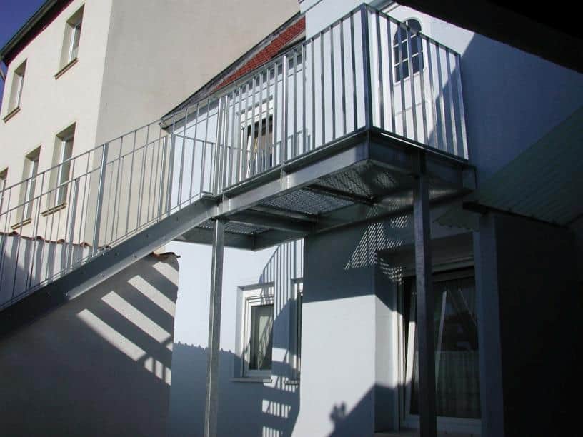Stahl Außentreppe Geradläufig verzinkt auf Stützen stehend als Außen Zugang zum 1 OG mit Podest & beidseitigem Treppengeländer als Stahlwangen Konstruktion & Flachhandlauf und Vierkant Geländerstäben & Gitterroststufen