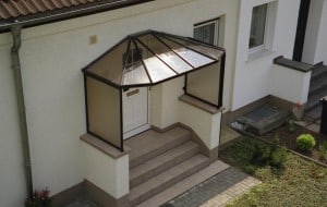 Aluminium Vordach beidseitig abgewalmt mit Seitenteil Links & Rechts auf Brüstungsmauerwerk montiert RAL 8019 Graubraun Acrylverglasung rauchbraun & Rinne & Fallrohr Farbe Braun